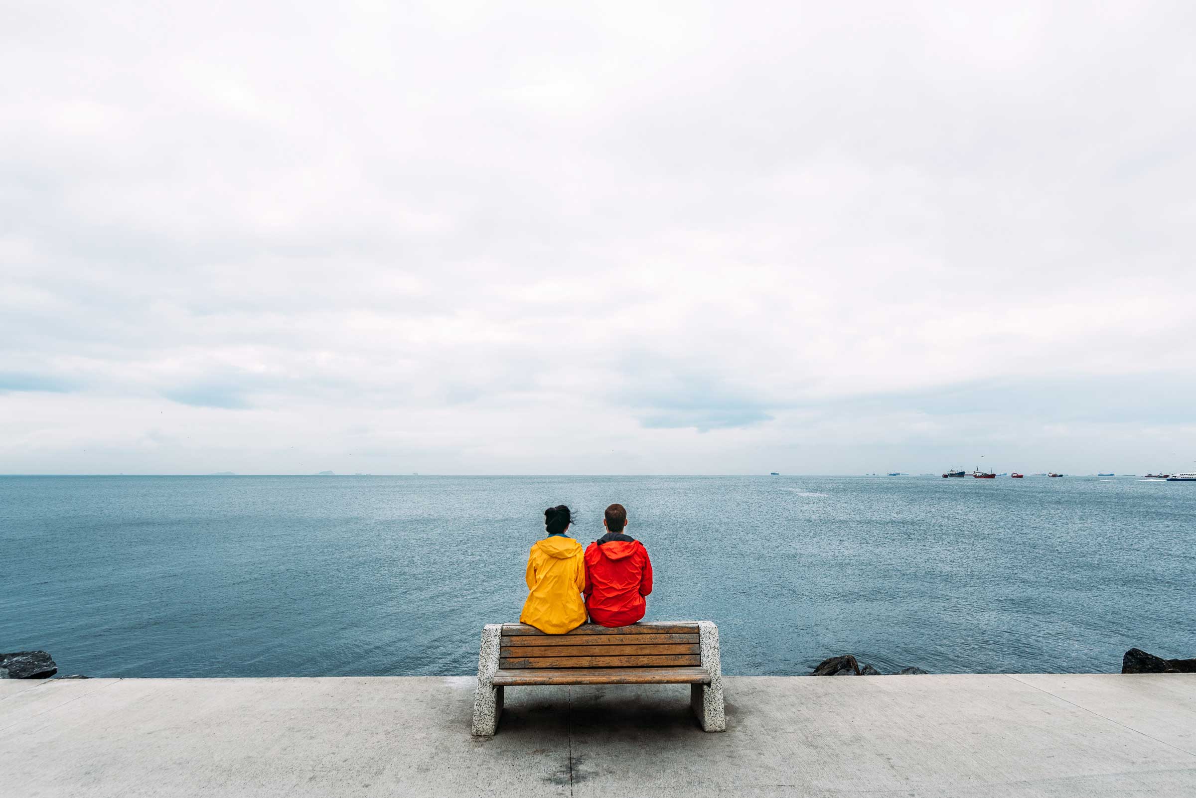 young-couple-sitting-on-a-bench-by-the-sea-man-an-2022-01-19-00-16-35-utc.jpg